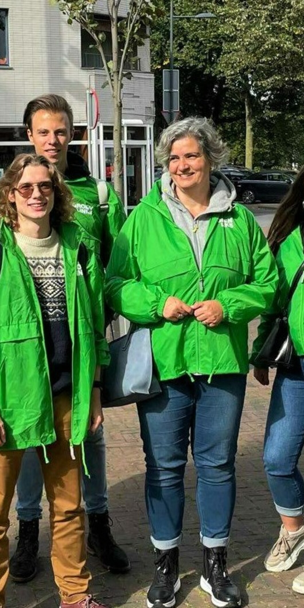 Een groep mensen in groenlinksjasjes op straat