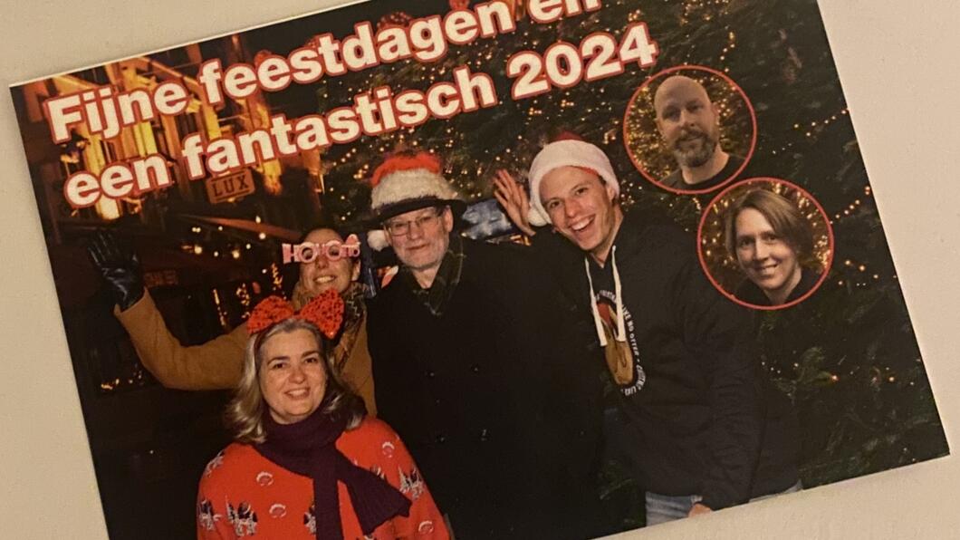 ansichtkaart met Wies, Yeliz, Hessel en Antoon voor een kerstboom, het portret van Nicole en Rick als kerstboombal